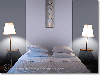 Pale blue bedroom walls with a white painted headboard & wooden ornament