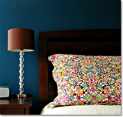 brown lamp and colored cushion against a navy blue wall