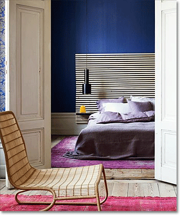 bedroom with red and purple rugs and a dark blue wall