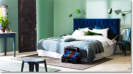 blue headboard set against jade colored bedroom walls