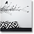 black sofa with black-and-white cushions and a black wall decal