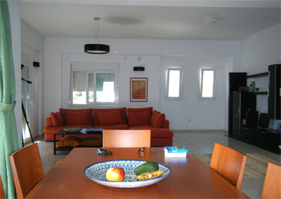 contemporary greek living room in white and cream, with a sofa in burnt orange