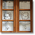 white tuscan renaissance cutwork curtain in a window frame