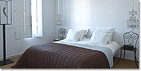 stark white walls and deep purple bedding in an austere French bedroom