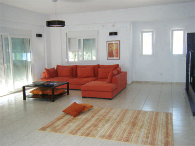 contemporary greek living room in white and cream, with a sofa in burnt orange