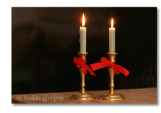 brass candle holders with white candles and red bows